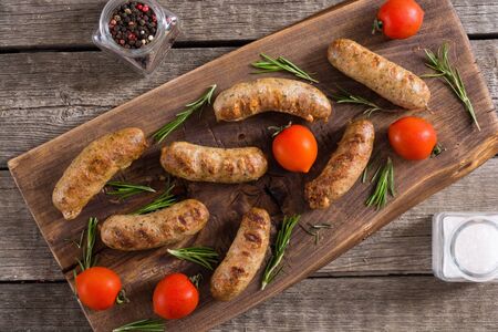 Grilled sausages with tomatoes , pepper and rosemary. BBQ food backgroundの写真素材
