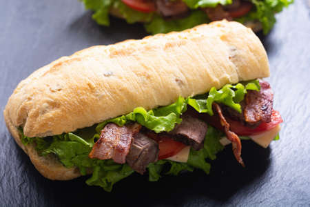 Big long sandwich with lattuce beef cheese and tomato