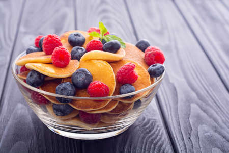 Mini pancakes with berries . Delicious breakfast . Food background