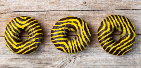 Set of colorful donuts on wooden background. Chocolate, lemon, orange and raspberry. Top viewの写真素材