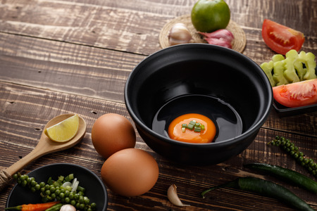 selective focus egg in bowl and ingredients on wood background side viewの写真素材