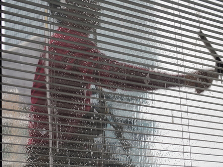 blurred man cleaning glass wall outside high rise buildinigの写真素材