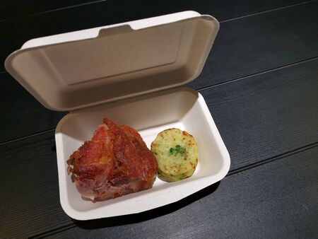 fried pork leg baked potato with spinach inside in disposable lunch boxの写真素材