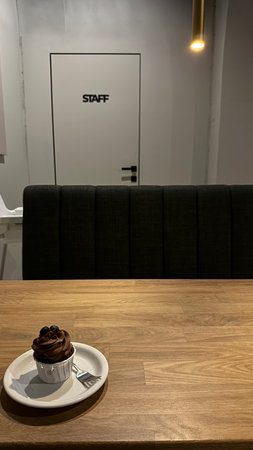 Cupcake on a wooden table in a cafe with a window in the backgroundの写真素材