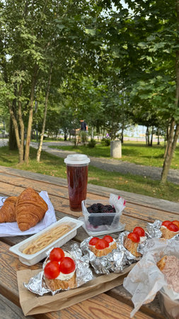 Picnic in the park on a wooden table with croissants and drinkの写真素材