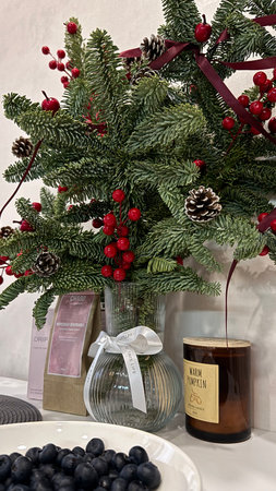 Christmas decoration with holly berry and pine cone in glass vaseの写真素材