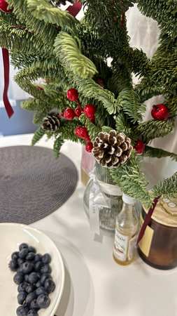 Decorated Christmas tree with berries and pine cones on white tableの写真素材