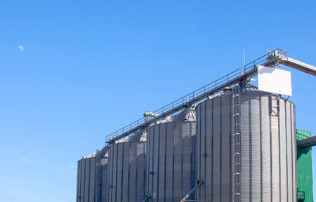 Storage tanks for cereal products over blue sky with moon