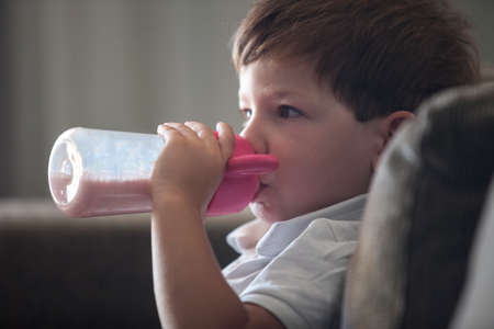 4 year old boy drinking with baby bottle. Stop using baby bottle concept
