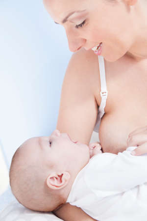 Happy young mother playing with her baby after feeding breastの写真素材