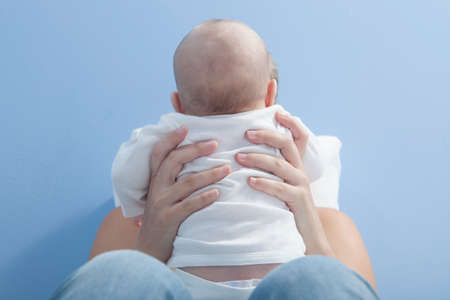 Happy young mother playing with her baby after feeding breast. She is holding the baby on her handsの写真素材