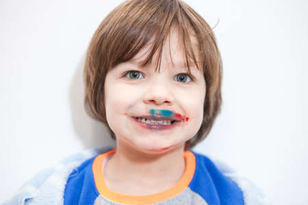 Little kid with mounth stained after eating cakes coated with synthetic food colorants. Food...
