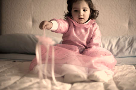 Little girl costumed as a fairy with magic wand sitting on the bed and playingの写真素材