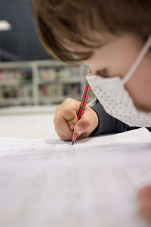 Pre-writer child boy doing calligraphy exercises with booklets. selective focus