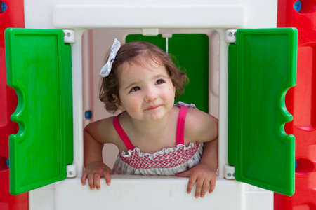 Little brown hair girl smiling through the window of kids playhouseの写真素材