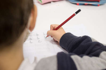 Pre-writer child boy doing calligraphy exercises with booklets. selective focus