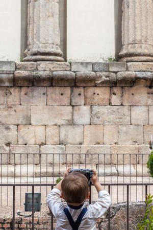 Cute little boy taking pictures to ancient roman temple. Cultural tourism with children conceptの写真素材
