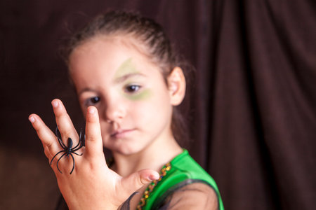 Little cute girl showing a spider during makeup process before halloween partyの写真素材