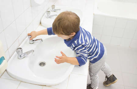 3 year old boy washing hands at adapted school sink. Learning hygiene habitsの写真素材