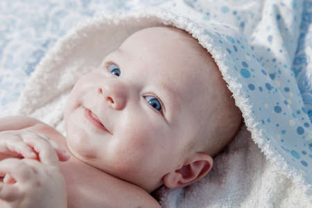 Cute three month baby wrapped bath towel after bath in bed at home