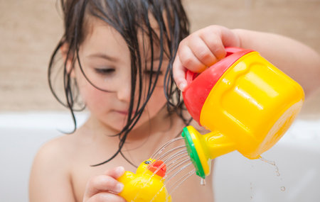 4 years little girl playing with rubber duck in the bathtube. Fun at bathing conceptの写真素材