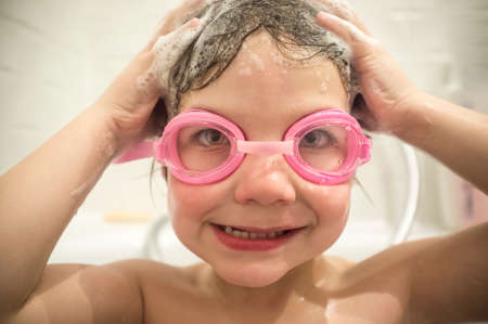 4 year old boy wearing goggles at bathtub. No more eyes stinging washing hair conceptの写真素材