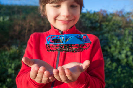Child boy playing with toy drone. Little quadcopter flying over her hands