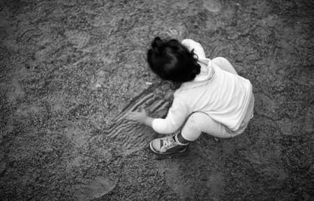 Brunette little girl back high view playing on park sandの写真素材