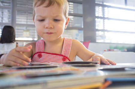 2 year old boy playing with tabs book at library. Discovering the books at his first visit at...