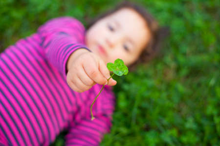 Happy three year old girl playing at grass meadow with clovers. selective focusの写真素材