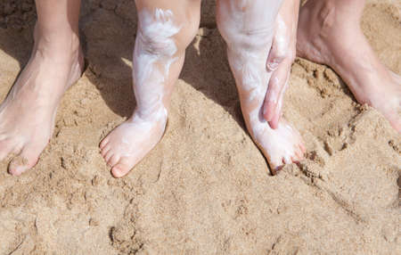 Mother applying sunblock cream to her baby on legs, El Rompido, Huelva, Spain