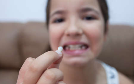 9 years old girl showing her first canine tooth fallen out. Selective focus