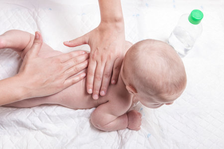 Three month baby boy receiving back massage from a female massage therapistの写真素材