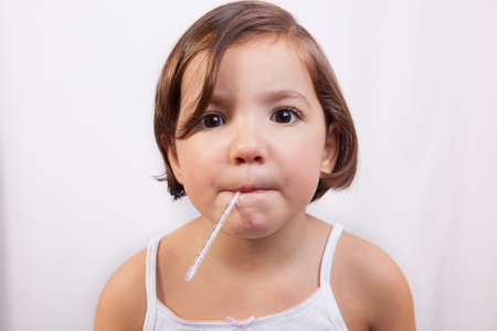 Little girl with a clinical mercury-in-glass thermometer in mouth looking to the cameraの写真素材