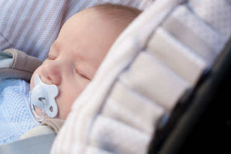 3 months baby boy sleeping in his stroller a sunny dayの写真素材