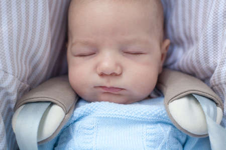 3 months baby boy sleeping in his stroller a sunny day