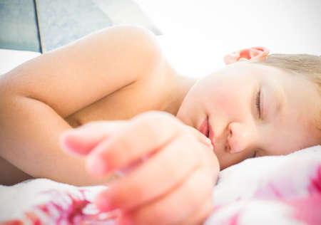 Toddler boy sleeping under beach umbrella shade. closeupの写真素材