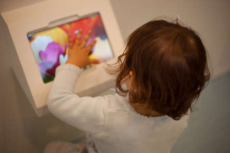 Baby girl playing with a digital tablet on a big shopping center