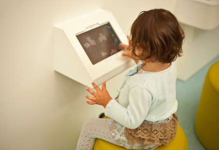 Baby girl playing with a digital tablet on a big shopping center