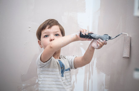 3 years cute little boy with paint roller in hand. Kids Helping House Chores conceptの写真素材