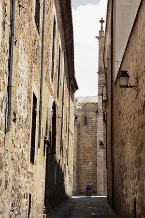 Biker crossing through the narrow streets of Caceres Old Town, Spainの写真素材