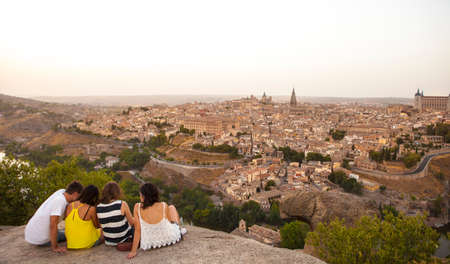 Toledo, Spain - July 27, 2016: Young people sitting on the stone enjoying peaceful magic moment of sunset over Toledo City, Spainのeditorial素材