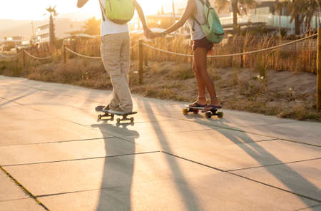Young couple skating together next to the beachの写真素材