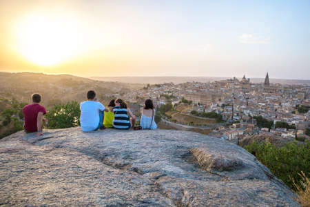 Toledo, Spain - July 27, 2016: Young people sitting on the stone enjoying peaceful magic moment of sunset over Toledo City, Spainのeditorial素材
