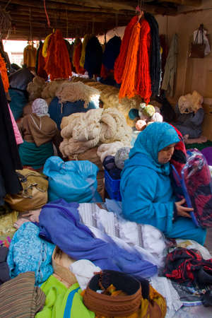 MARRAKESH - JANUARY 21: Arabic women at fabrics market with blankets and hanging woolen yarns, Jan 21, 2010 Marrakesh, Moroccoのeditorial素材