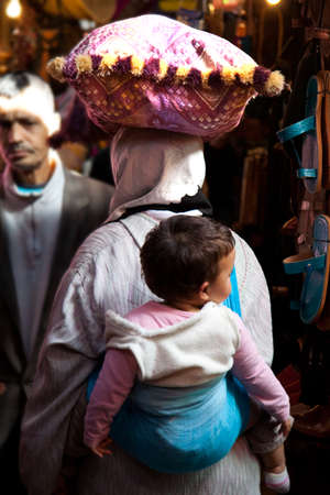 MARRAKESH, MOROCCO - JAN 21: Unidentified woman carrying their children in her backpack on January 21, 2010 in Marrakesh, Moroccoのeditorial素材