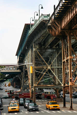 NEW YORK - JUN 22: Elevated train tracks and station buildings cast the streets below into shadow in...