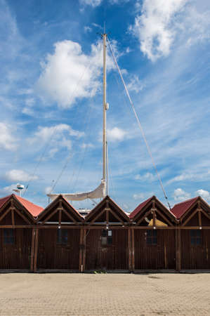 Fishermen huts of Cabanas de Tavira, Portugal. Cloudy blue sky and high mast as background