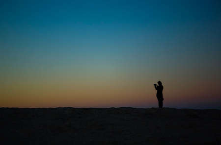 Woman taking pictures at San Vicente cape at sunsetの写真素材