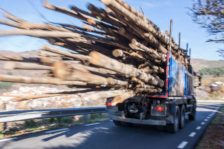 Log truck rushes down the mountain road. Truck Car in motion blurの写真素材